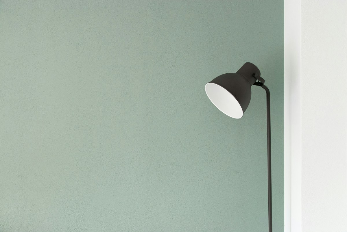 A reading lamp against a pale green wall